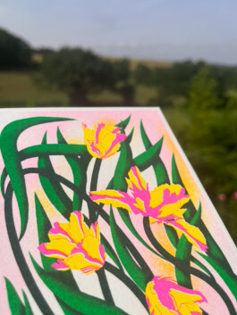 Zoom sur un carte postale illustrée de tulipes en risographie par Yollema, sur fond de prairie
