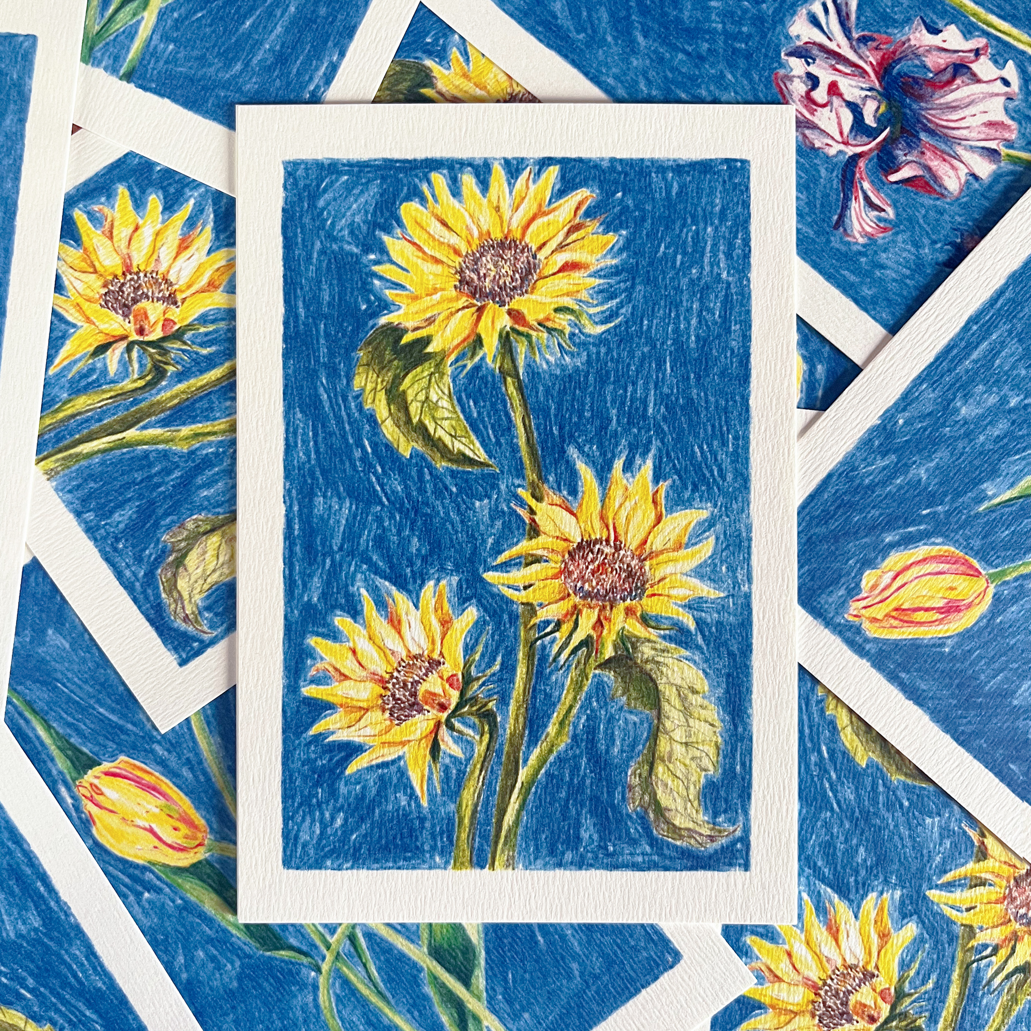 Carte postale fleurie illustrée de tournesols par Yollema posée sur une pile de cartes