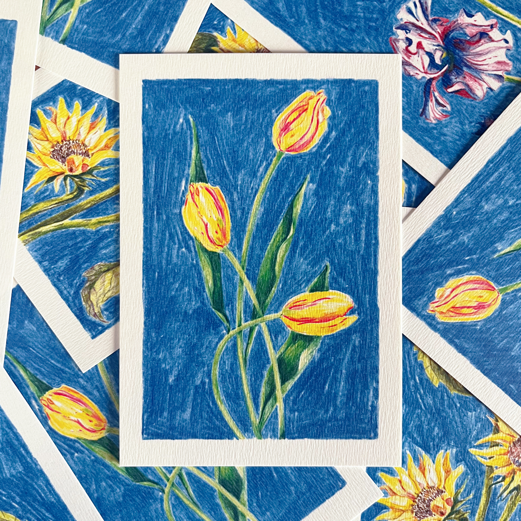 Carte postale fleurie illustrée de tulipes par Yollema posée sur une pile de cartes