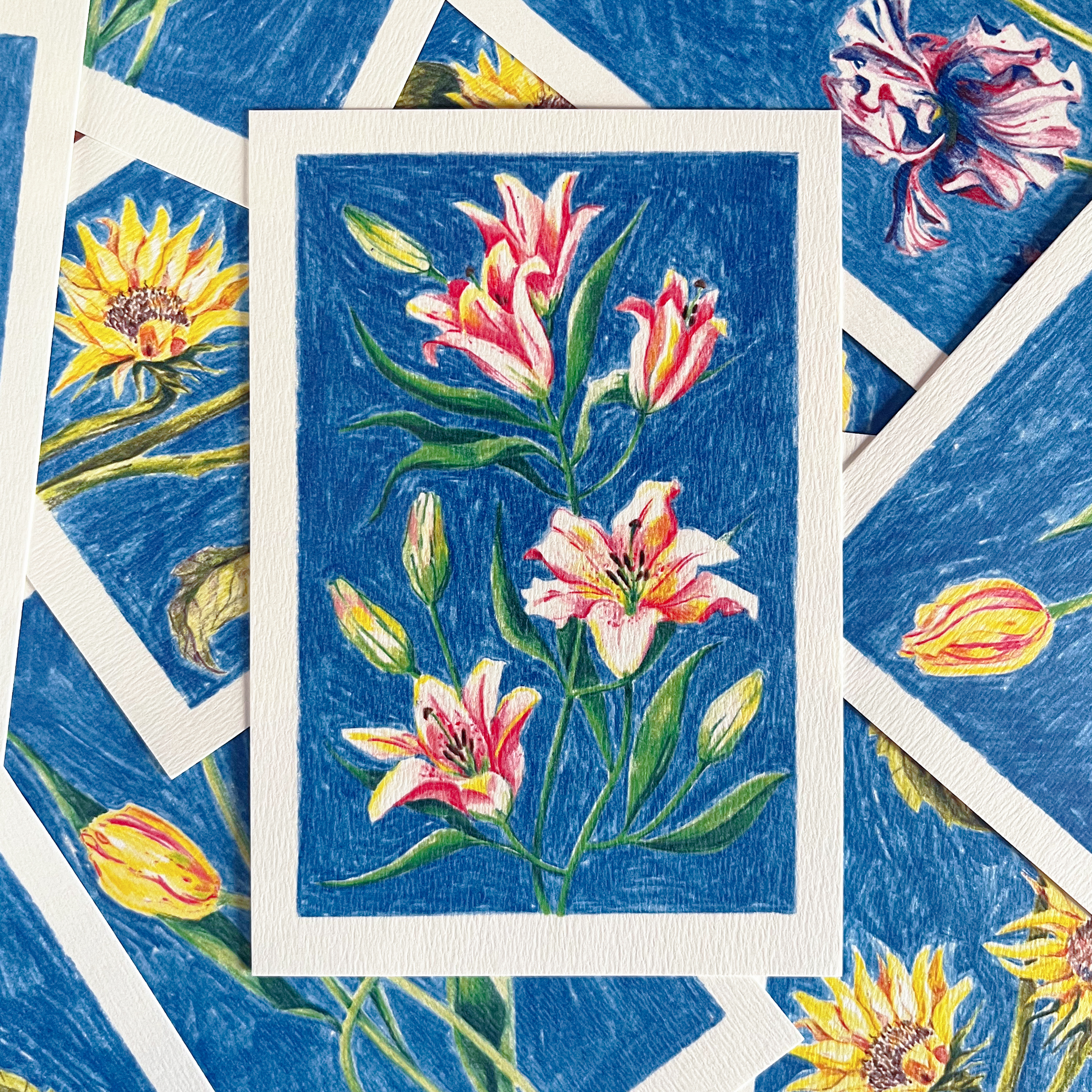 Carte postale fleurie illustrée de lys par Yollema posée sur une pile de cartes