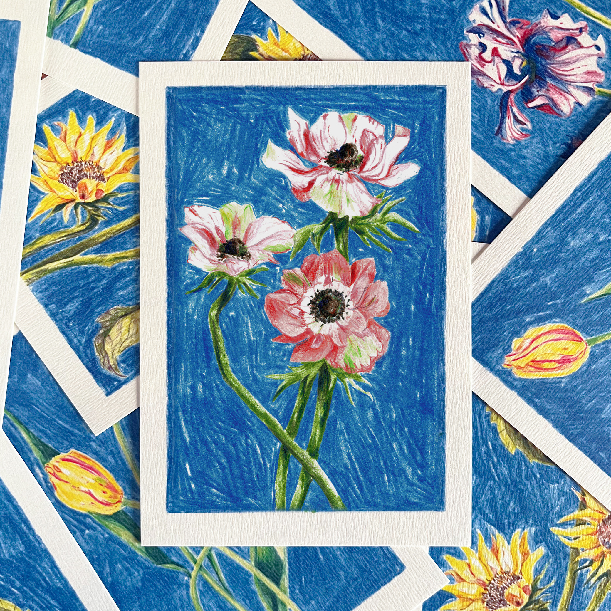 Carte postale fleurie illustrée d'anémones par Yollema posée sur une pile de cartes