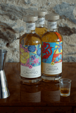 Trois bouteilles de rhum avec des étiquettes illustrées très colorées et un petit verre devant 