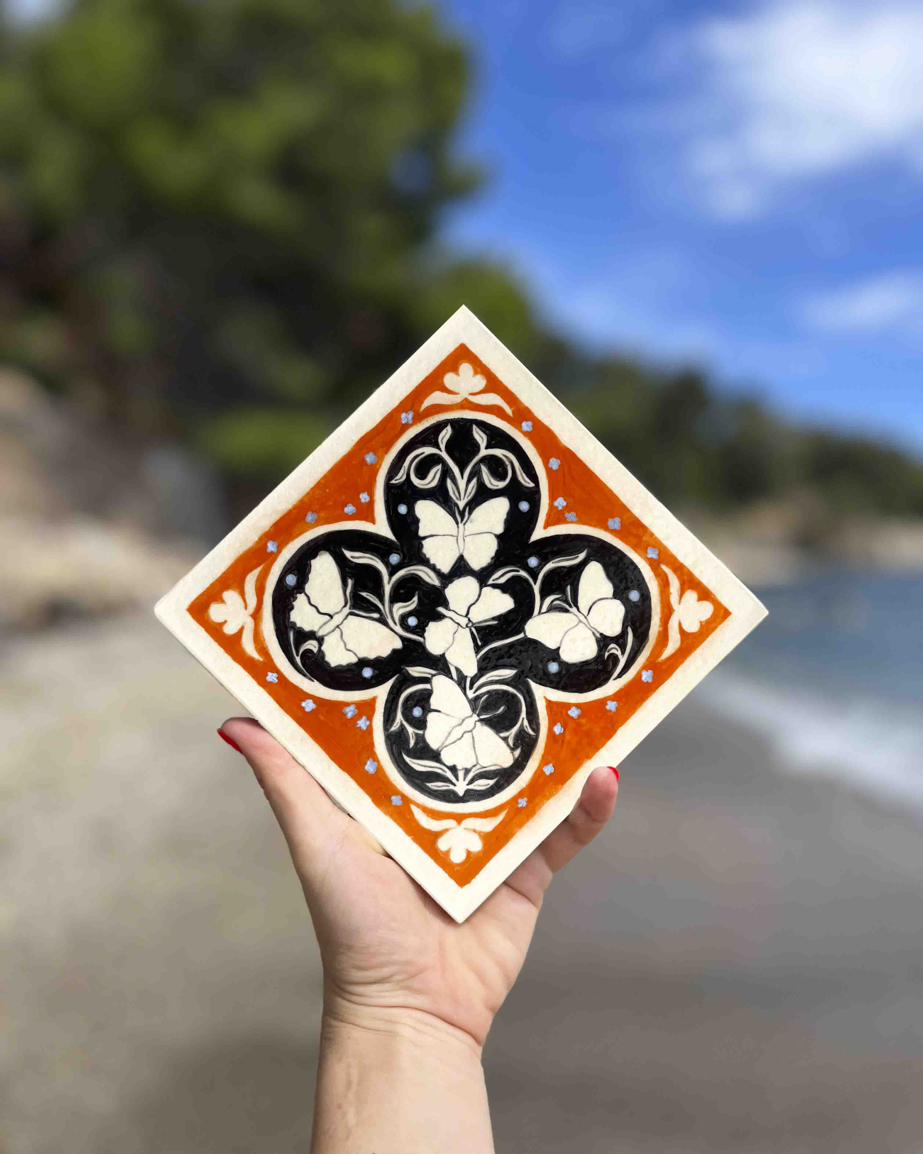 Carreau de grès vert clair et noir fait par Yollema représentant six papillons tenu par une main