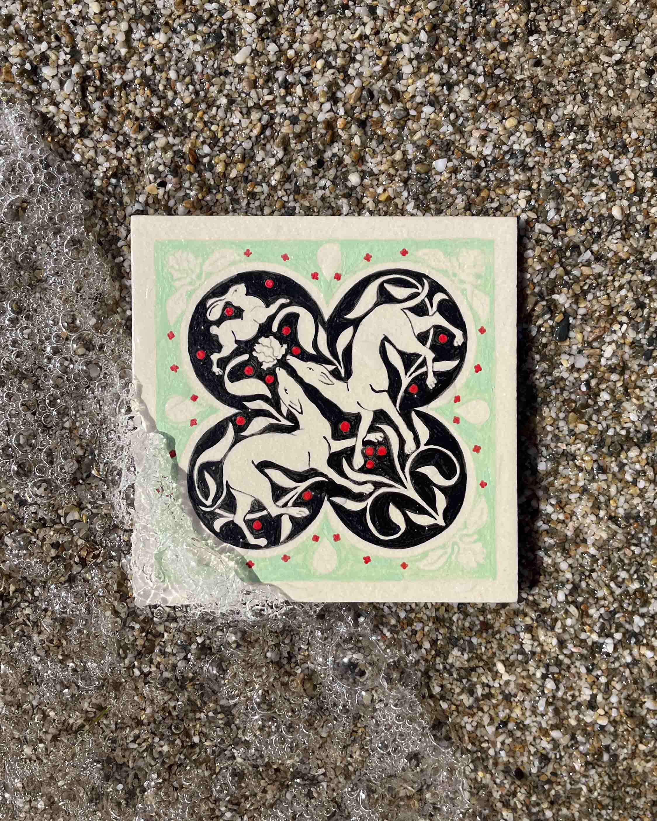 Carreau de grès fait par Yollema représentant deux lévriers et un lapin sur la plage vu du dessus