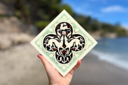 Carreau de grès vert clair et noir fait par Yollema représentant deux lévriers et un lapin tenu par une main