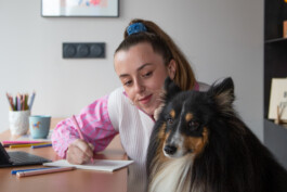 Portrait de l'illustratrice Yollema en train de dessiner dans son atelier avec son chien sheltie Otto