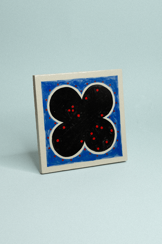 Carreau de grès décoratif, peint à la main, bleu et noir avec des points rouges.