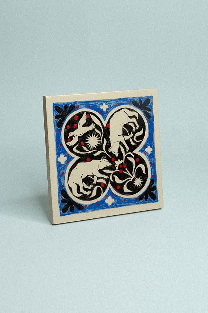 Carreau de grès décoratif, peint à la main, bleu et noir avec motif graphique symétrique fleuri résentant deux loups et une oie.