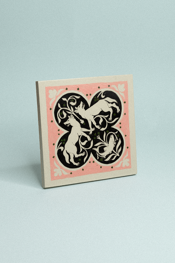 Carreau en grès peint à la main, dans les tons rose pâle et noir avec motif symétrique représentant deux renards et un poisson.