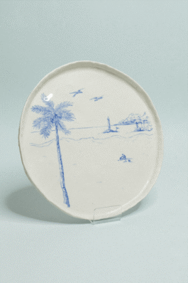 Assiette en porcelaine illustrée au crayon d’oxyde bleu représentant un palmier et des détails de paysage côtier minimalistes 