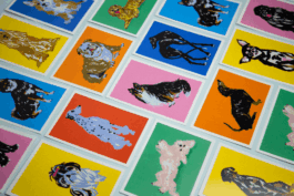 Lot de cartes postales très colorées, illustrées de chien de race différentes, posées côte à côte.